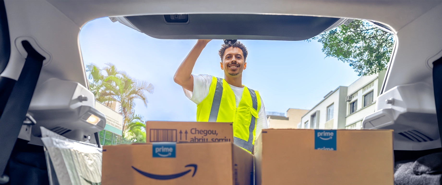 a man in a yellow safety vest looking at packages in his trunk
