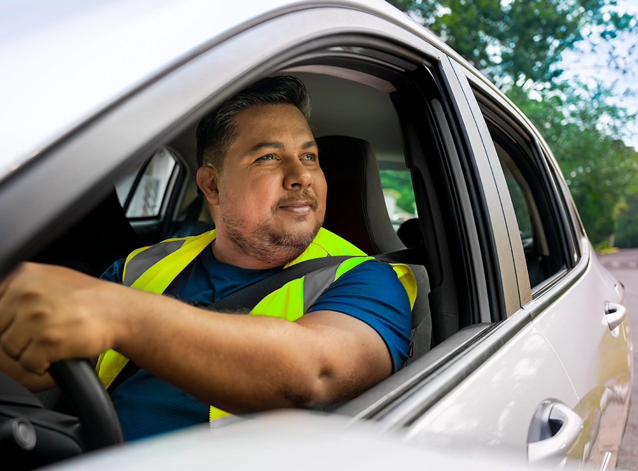 homem vestindo um colete de segurança amarelo enquanto dirige um carro